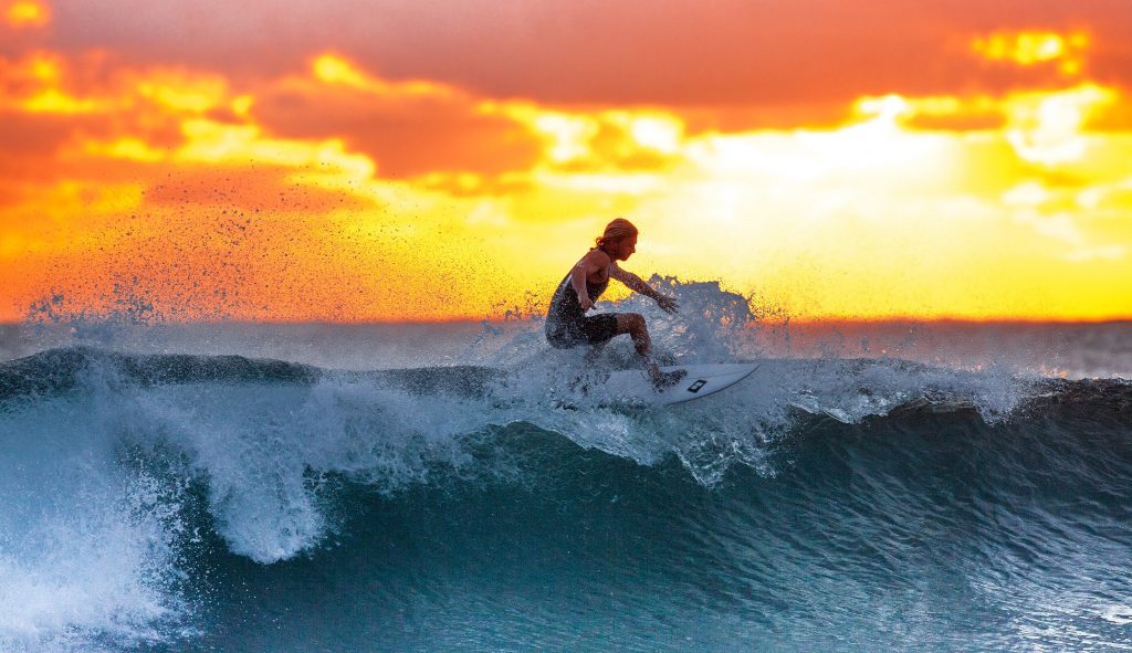 Let go of negative self-beliefs image of guy surfing in the sunset