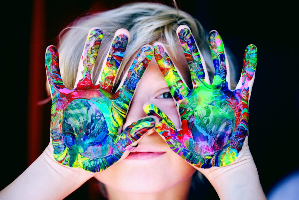 child with paint on hands using creativity to find true self